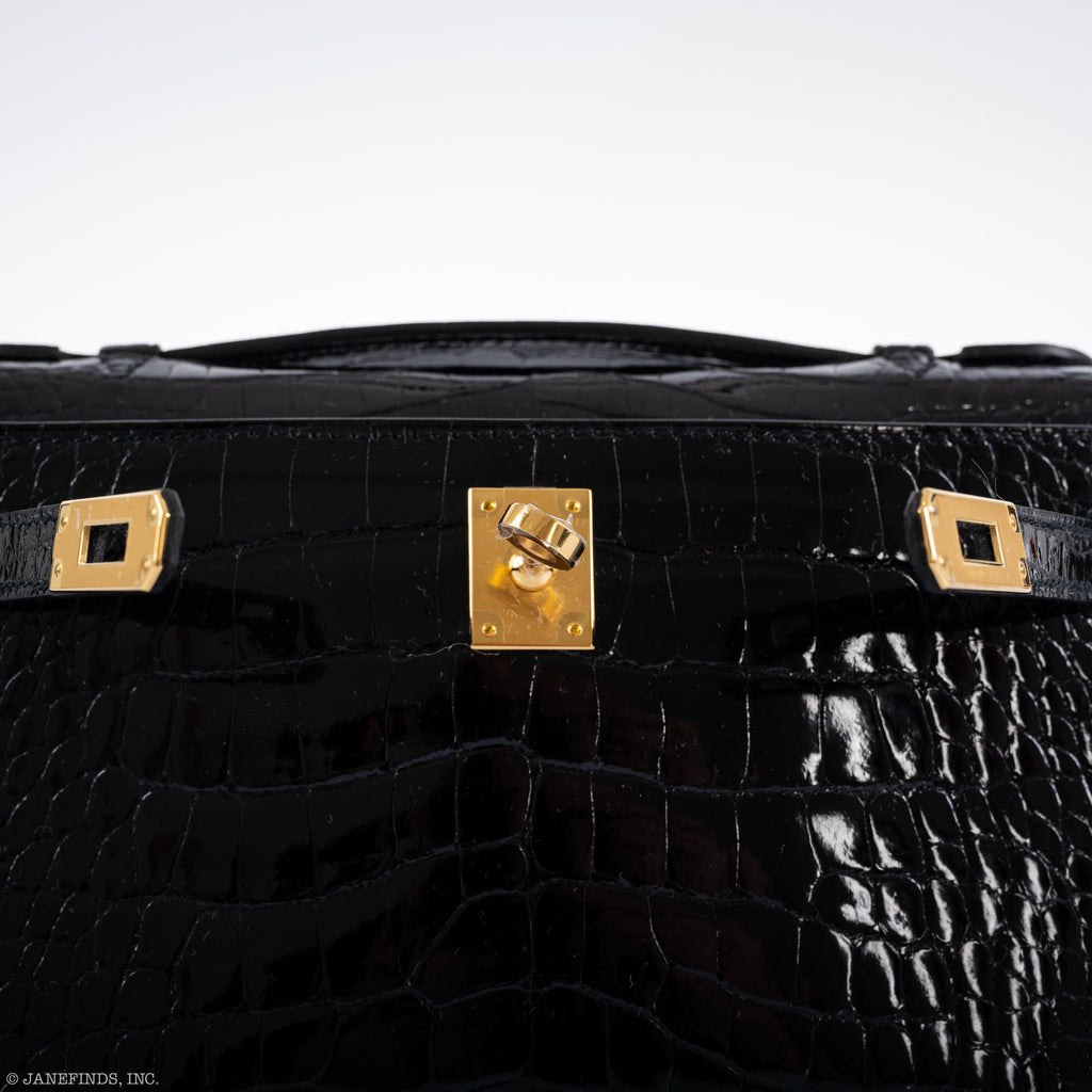 Black crocodile skin suitcase with gold hardware on a white background