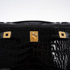 Black crocodile skin suitcase with gold hardware on a white background