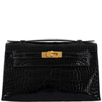 Black crocodile skin handbag with a gold clasp on a white background
