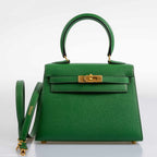 The Hermes Kelly Mini Pochette being held by hand, showcasing its compact size and top handle