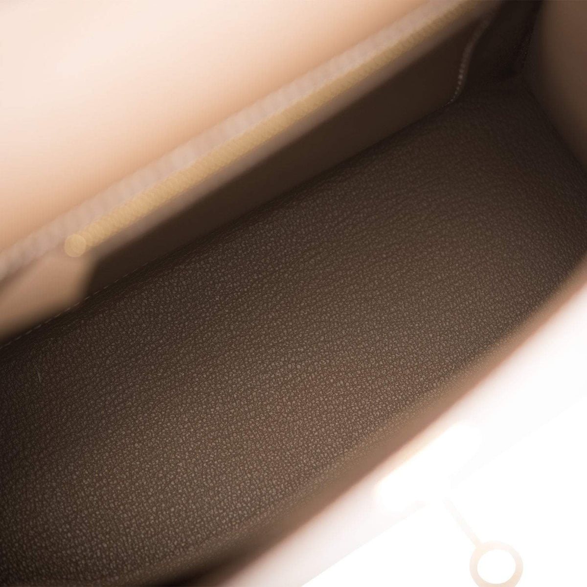 A close-up of the base of the handbag, showing the protective metal feet