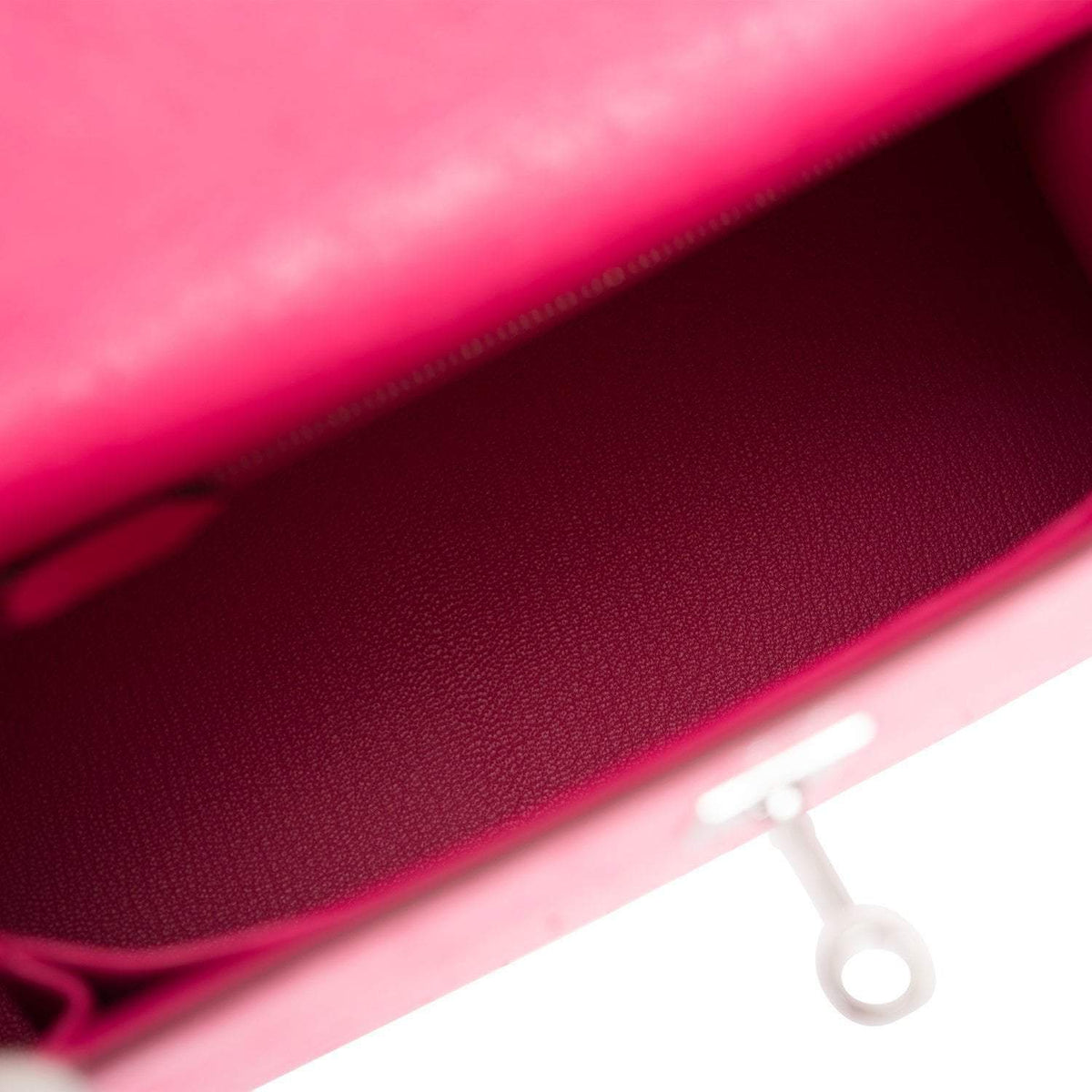 The Rose Tyrien Ostrich Kelly 25 being held by a hand, showing its compact scale