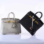 The Hermes Micro Kelly Charm in black lizard, attached to a chain